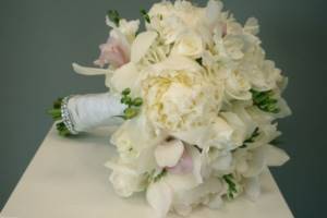 Bouquet of peons, roses and orchids decorated with silk ribbons, rhinestones and greenery