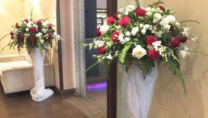 Two tall vases with red and white roses at the entrance to the hall
