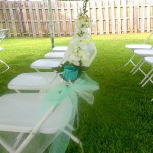 photo of wedding chairs with green bows