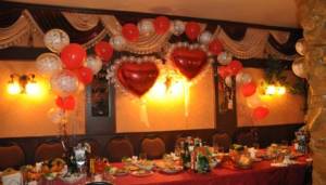 Beautiful red foil heart balloons above the chairs for the bride and groom