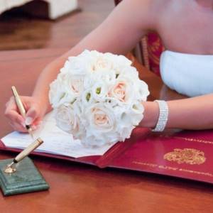 невеста ставит подпись после регистрации в ЗАГСе