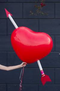 Heart-shaped ball pierced by cupid&#39;s arrow