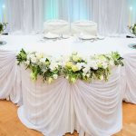 Wedding table with white decorative fabric and candlesticks