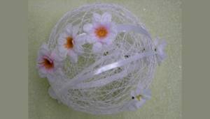 A light ball of knitting threads with flowers as a wedding hall decoration