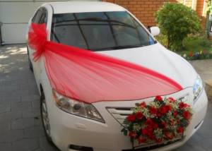 decorating a car for a wedding with ribbons
