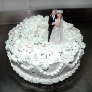 украшенный фигурками жениха и невесты торт из сливок