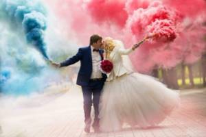 Bride and groom with colored smoke bombs